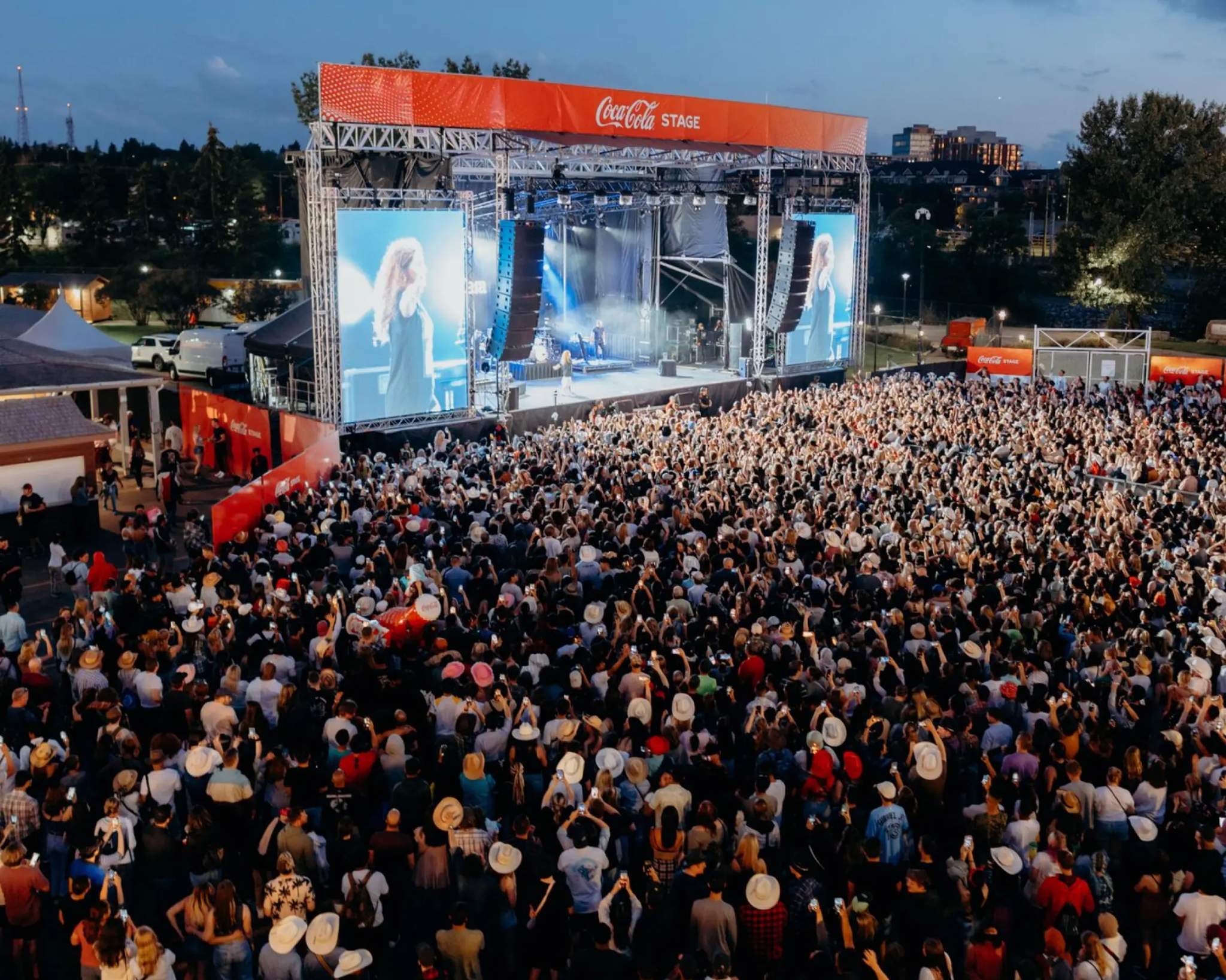 Festivalartist på scen inför en stor publik i solnedgången